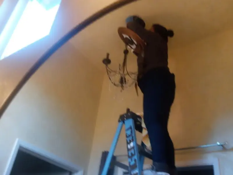 Electrician installing a chandelier in a Bystrom residence